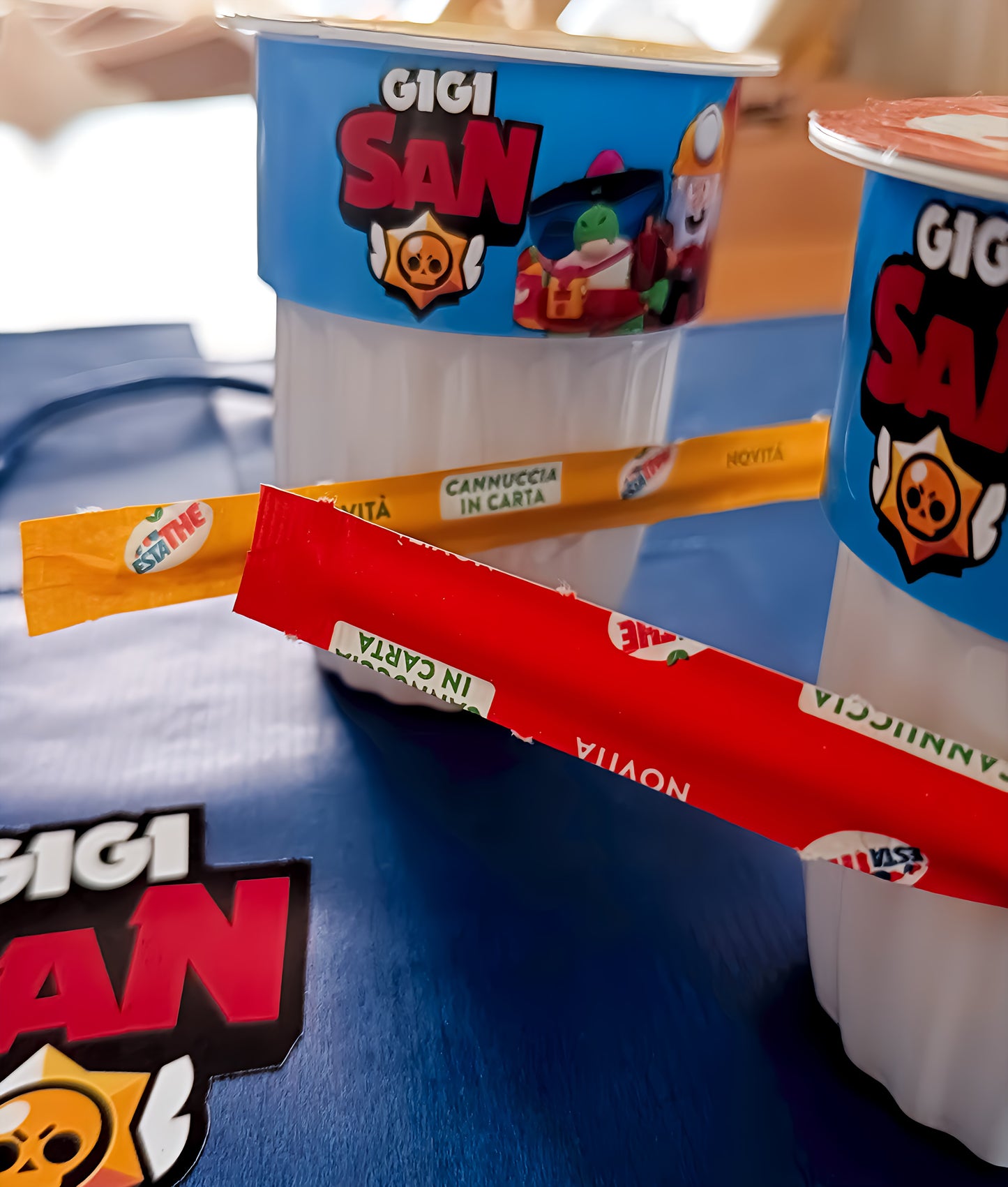 Gigi San yogurt cup with colorful packaging, cartoon characters, and paper straws labeled 'Novità'.