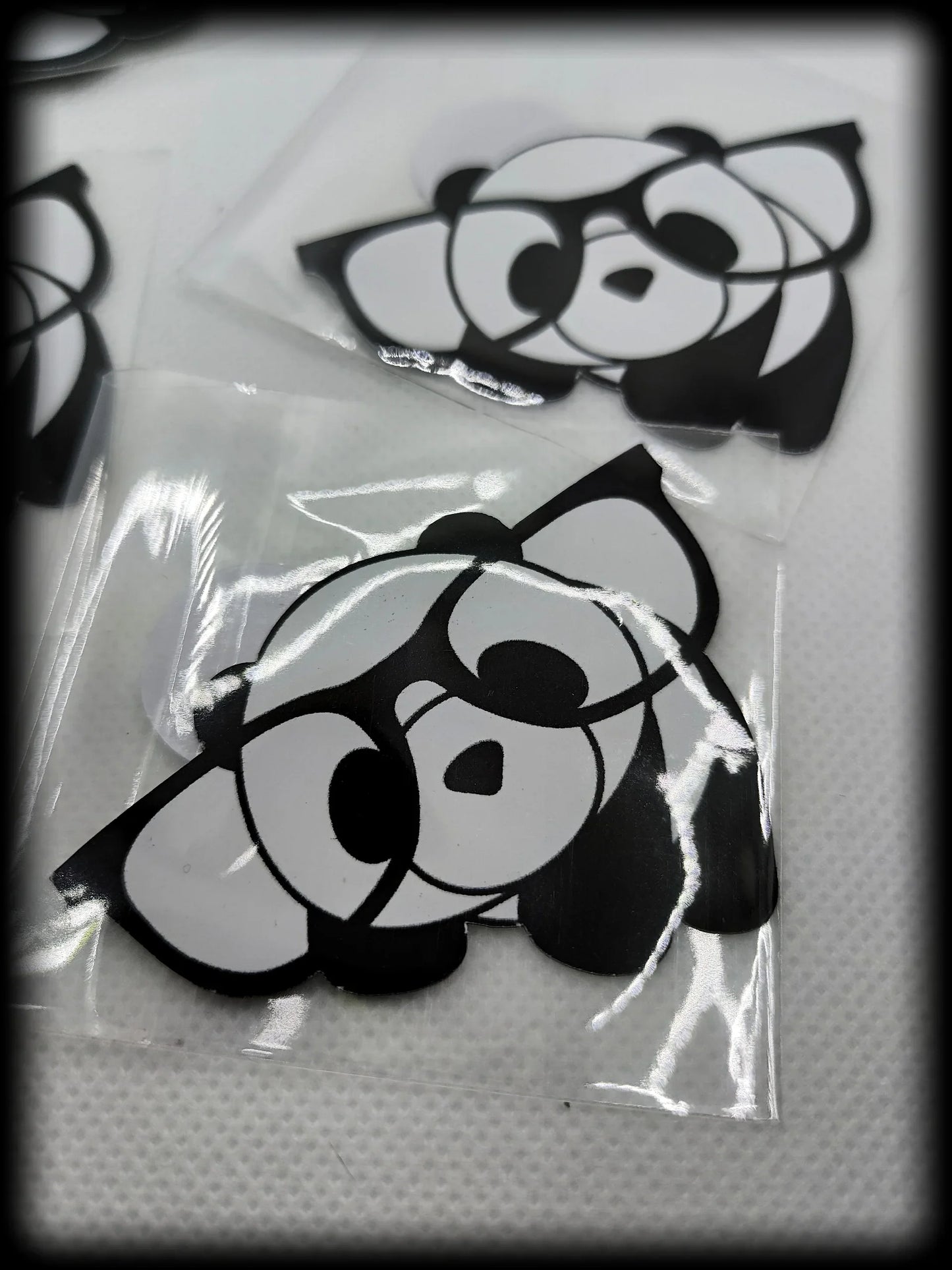 Black and white cartoon panda stickers on textured white surface in plastic sleeves