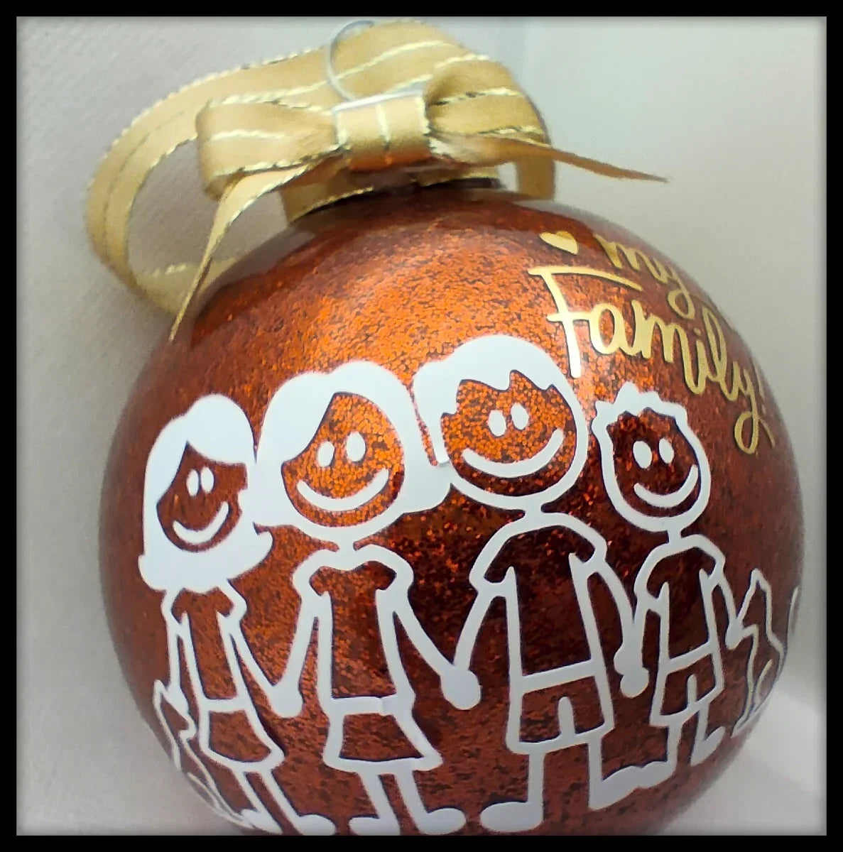 Red glitter Christmas ornament with stick figure family design and gold ribbon bow