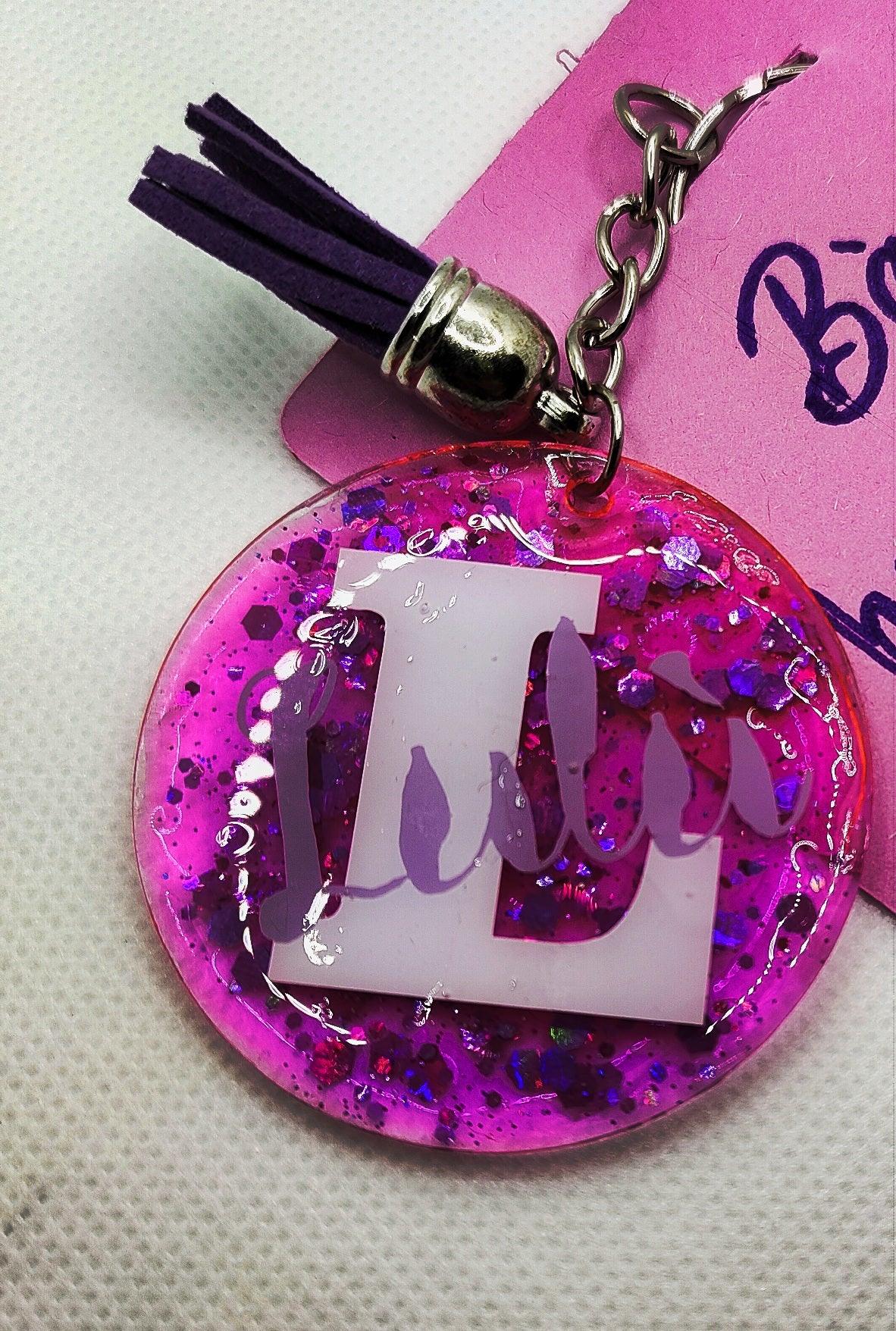Pink glitter resin keychain with purple tassel and large white L initial charm