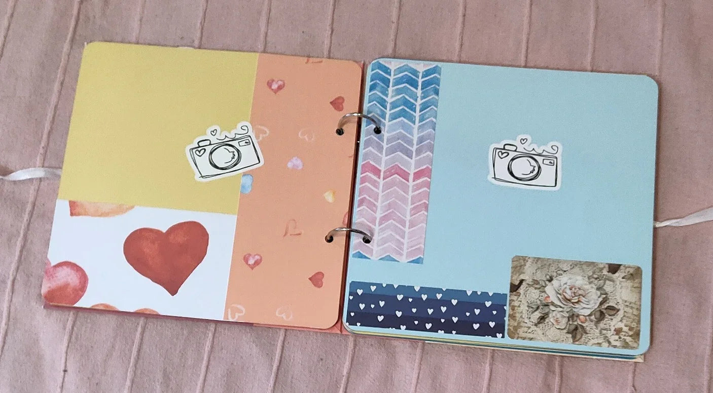 Open scrapbook with colorful heart and camera stickers, floral and chevron patterns on pages