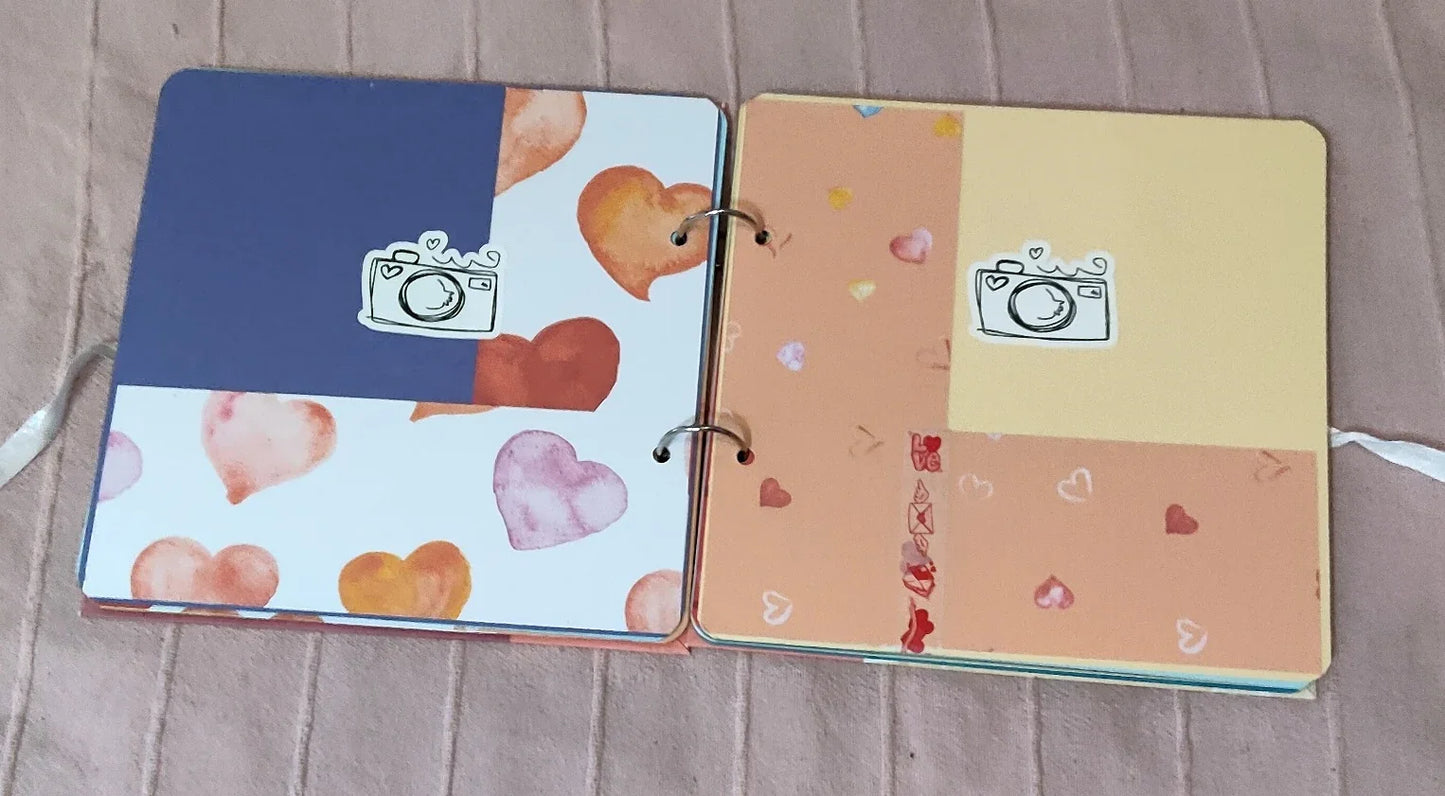Colorful scrapbook open to heart-patterned and pastel pages with camera stickers