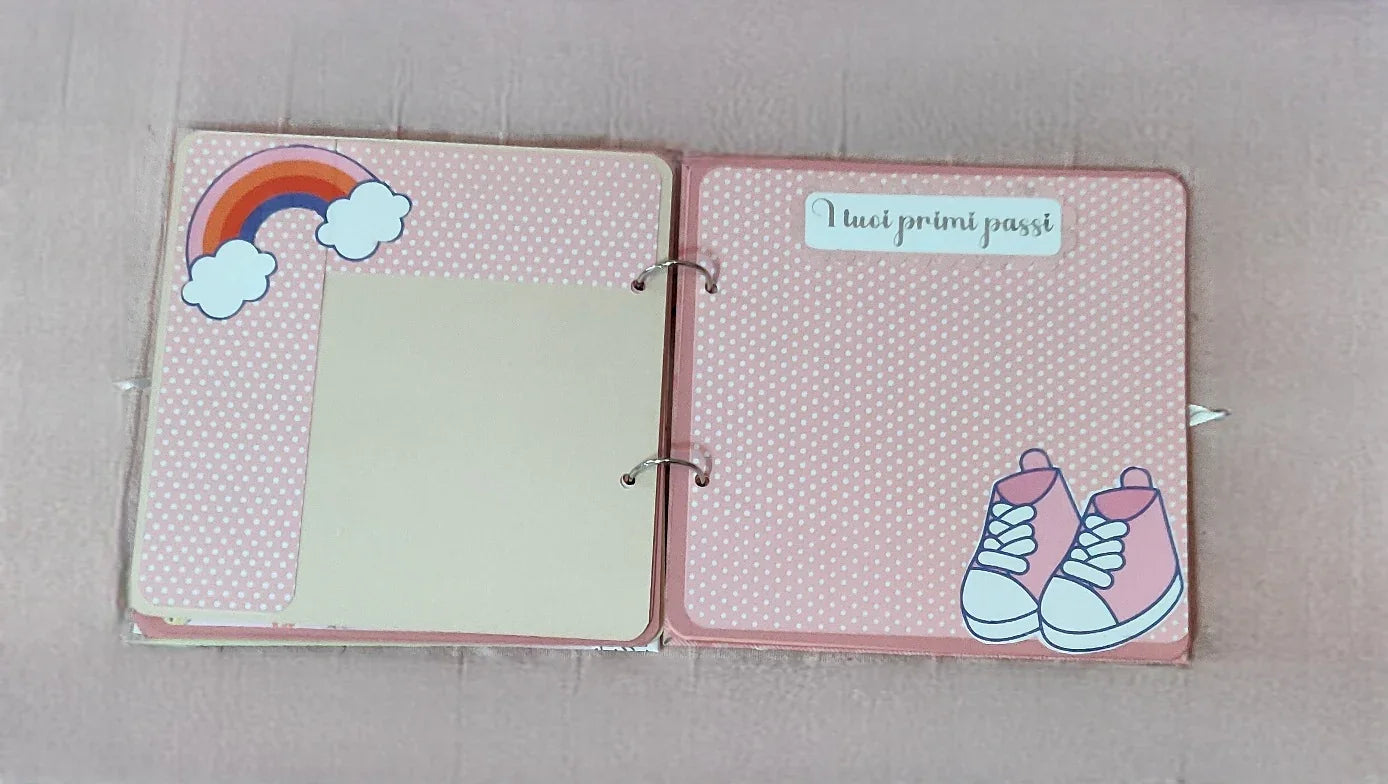 Pink baby memory book pages with polka dots, rainbow, sneakers, and Italian text 'I tuoi primi passi'.