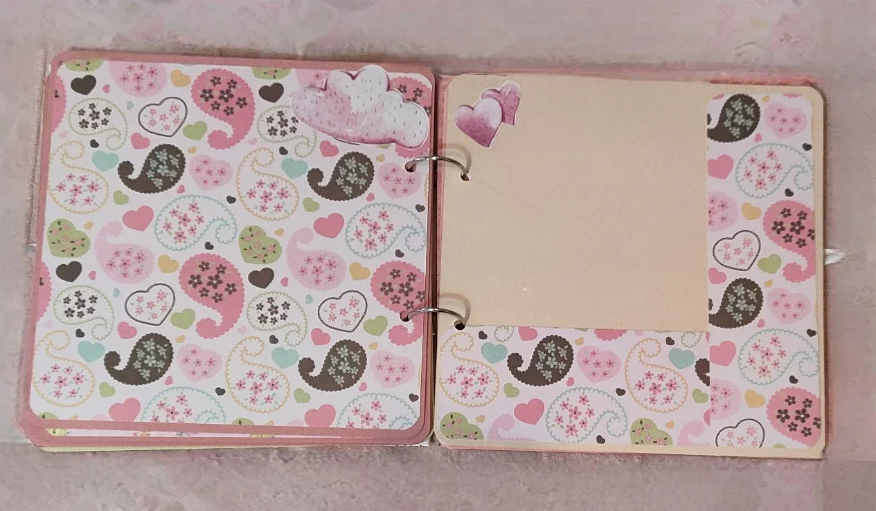 Handmade scrapbook album with heart and paisley patterns in pink, green, and brown.