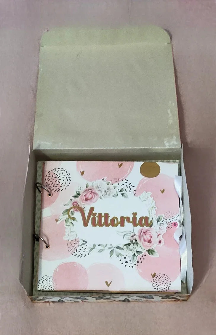 Personalized floral scrapbook with 'Vittoria' on the cover in a gift box, pink background