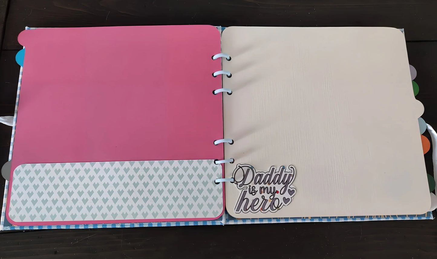 Open scrapbook with pink and cream pages, heart pattern, and 'Daddy is my hero' text.