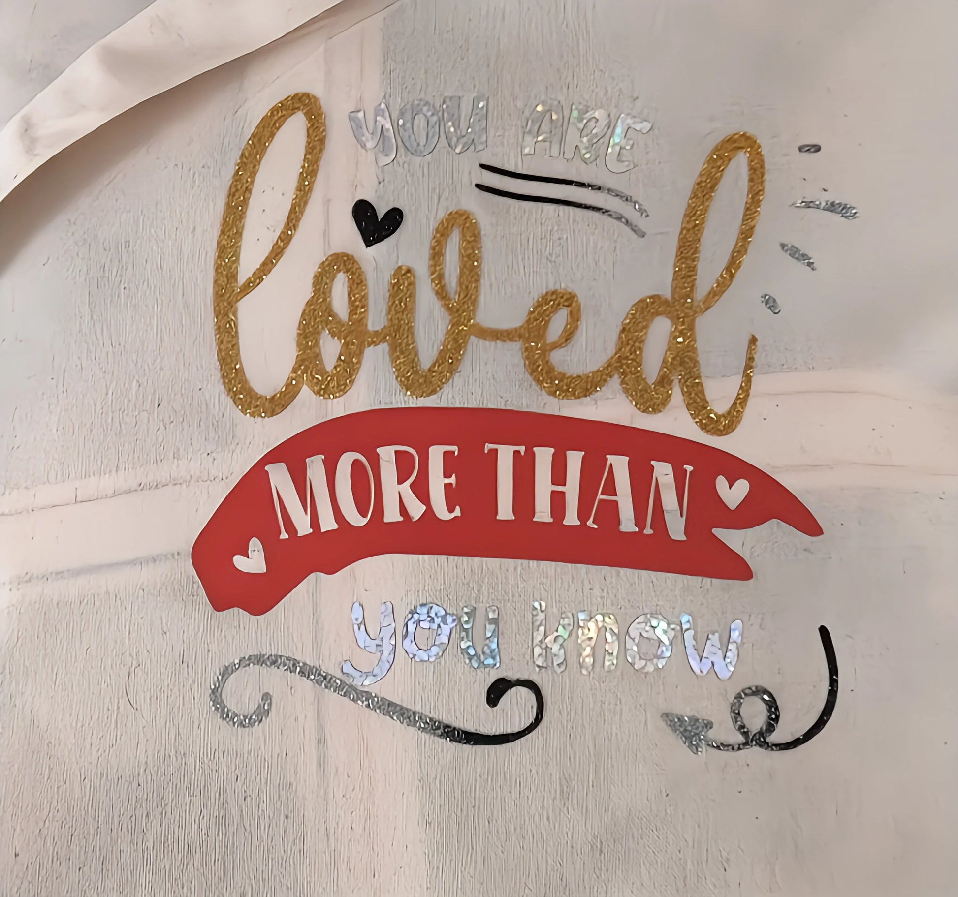 Inspirational wall sign with 'You are loved more than you know' in gold, red, and silver.