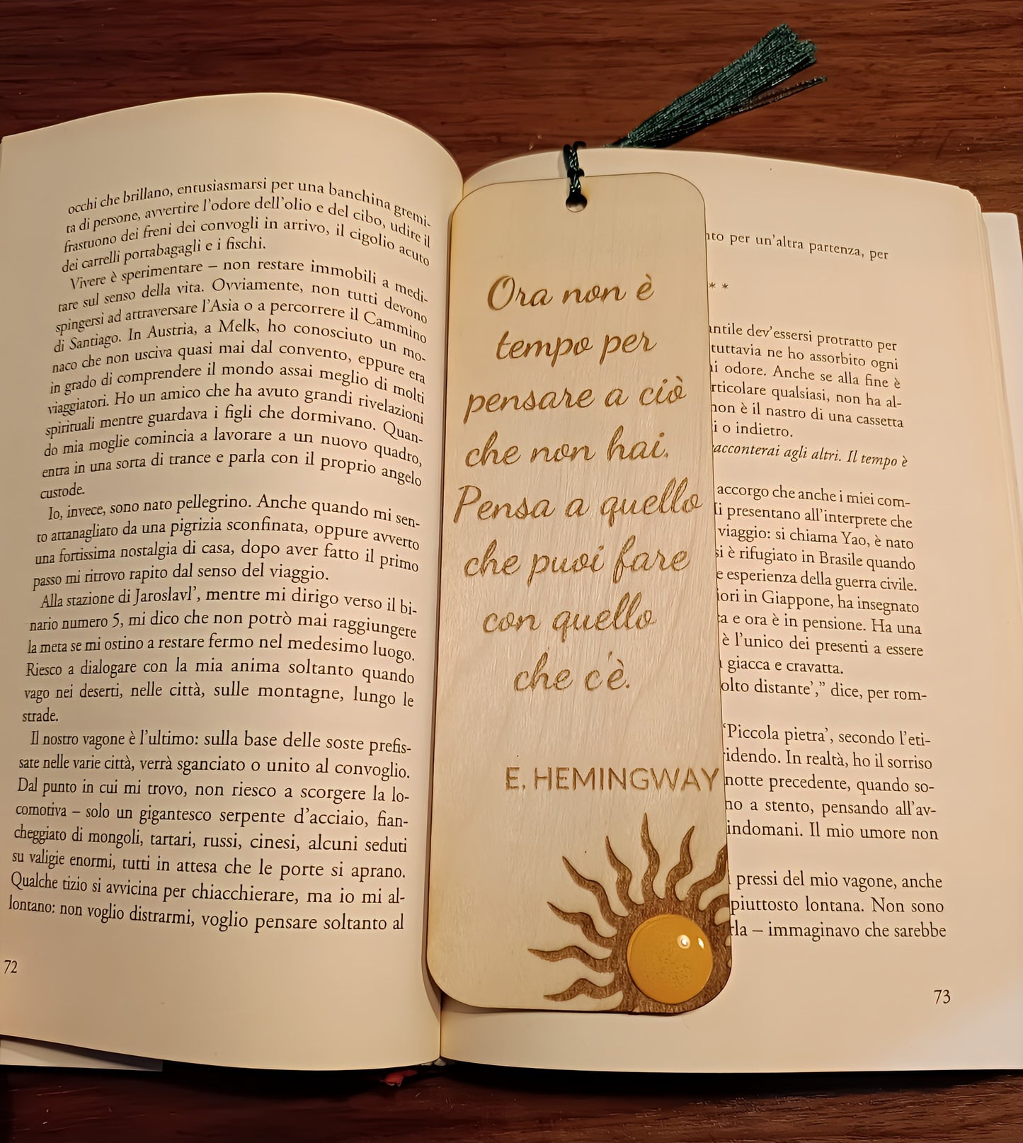 Wooden Hemingway quote bookmark with sun design inside open Italian book on wooden table