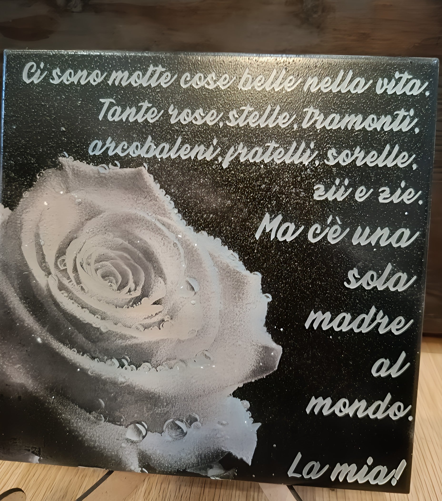 Decorative plaque with Italian text and a black-and-white rose with water droplets