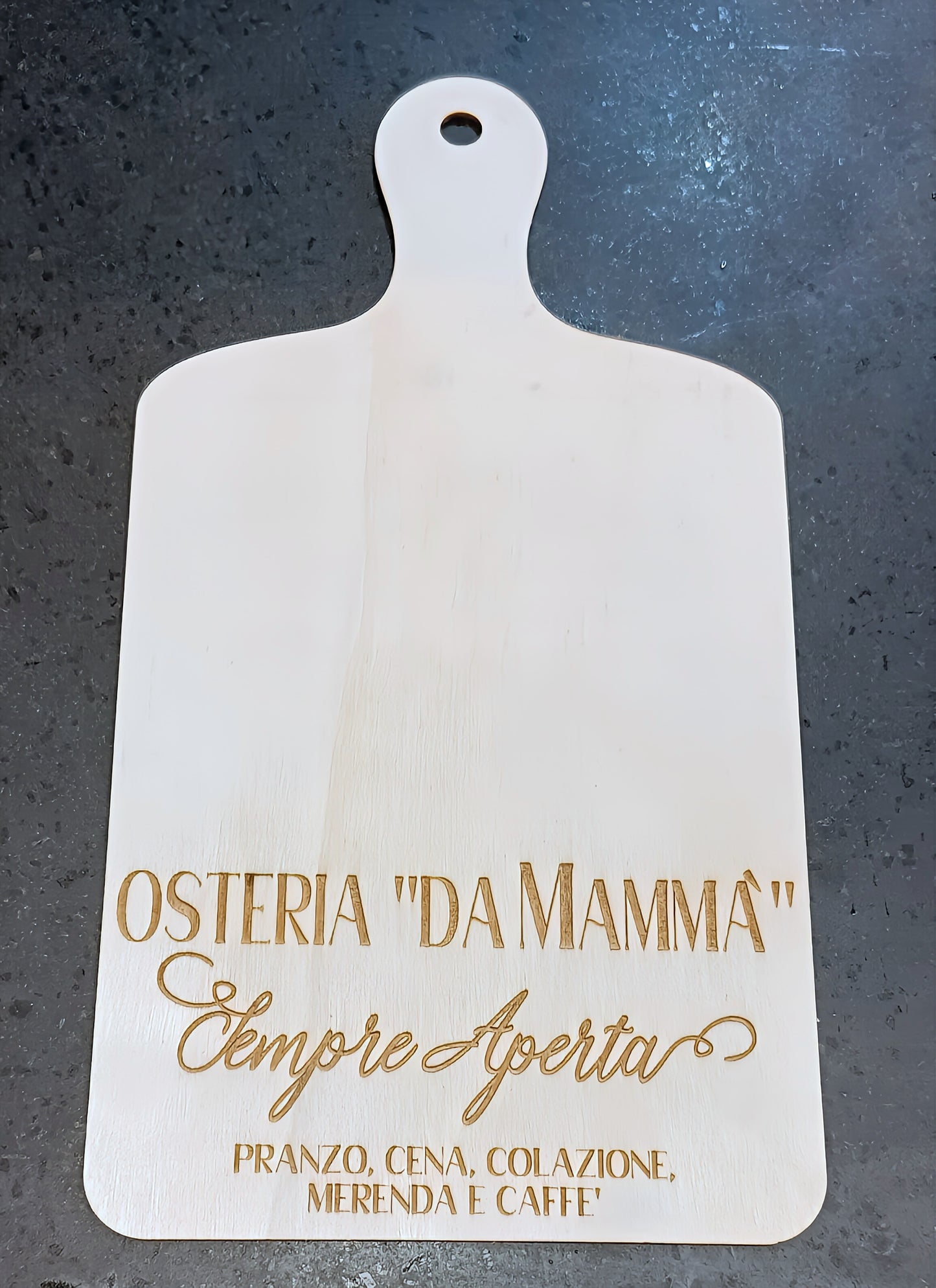 White wooden cutting board with Italian engraved text on dark countertop