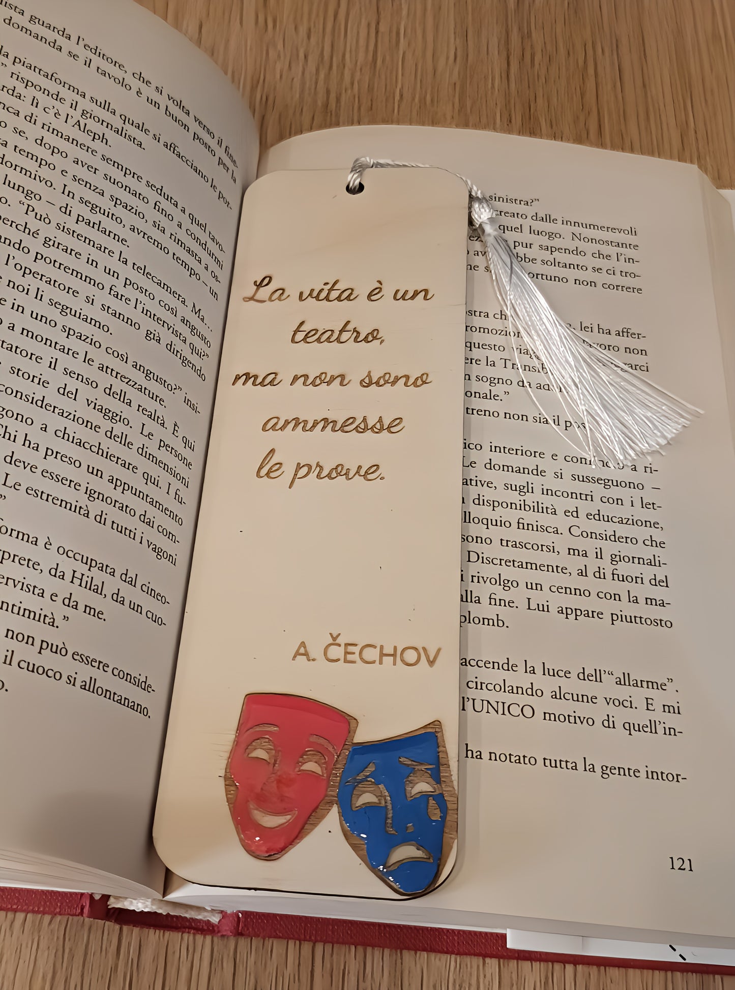 Bookmark with Chekhov quote and theater masks on open Italian book on wooden table