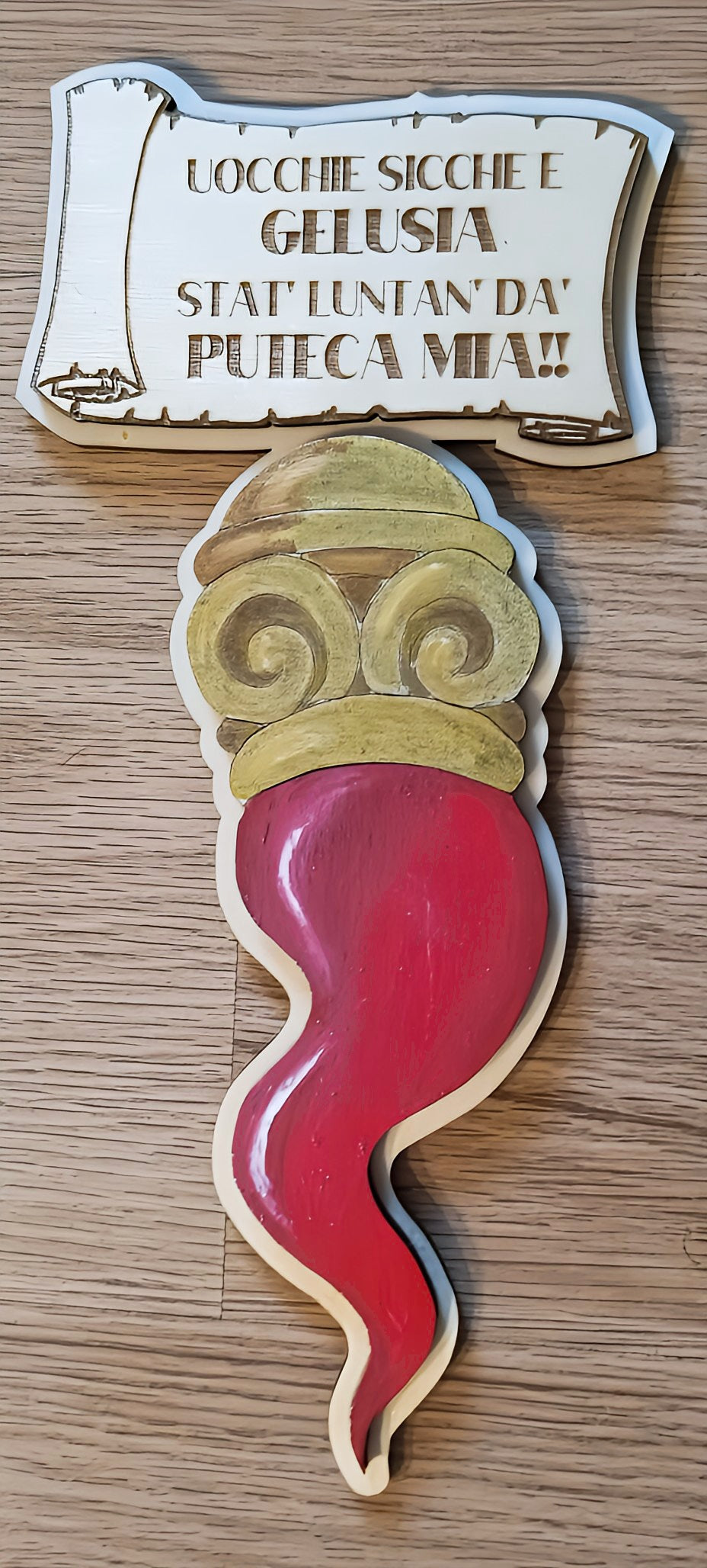 Wooden Italian cornicello charm with engraved Neapolitan saying on wooden background