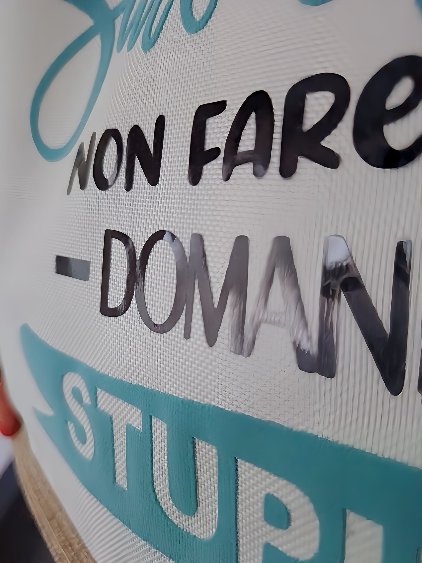 Close-up of Italian text on textured white fabric banner with turquoise and black lettering