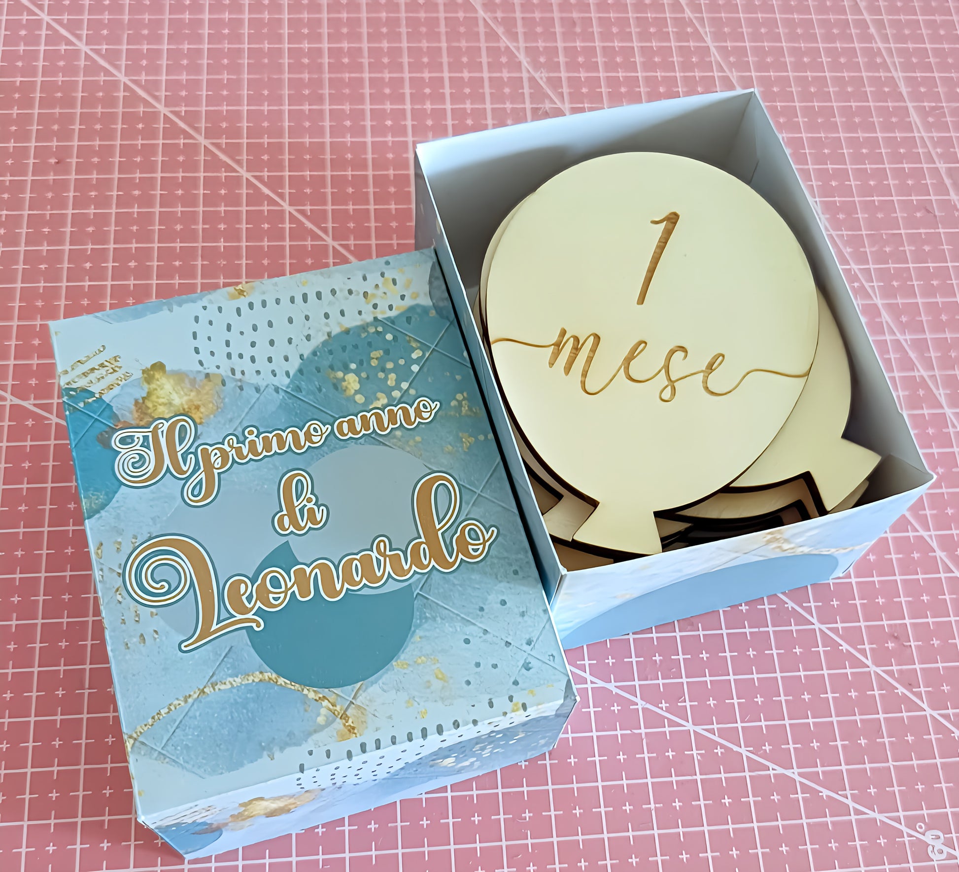 Decorative box with 'Il primo anno di Leonardo' and wooden milestone marker '1 mese'.