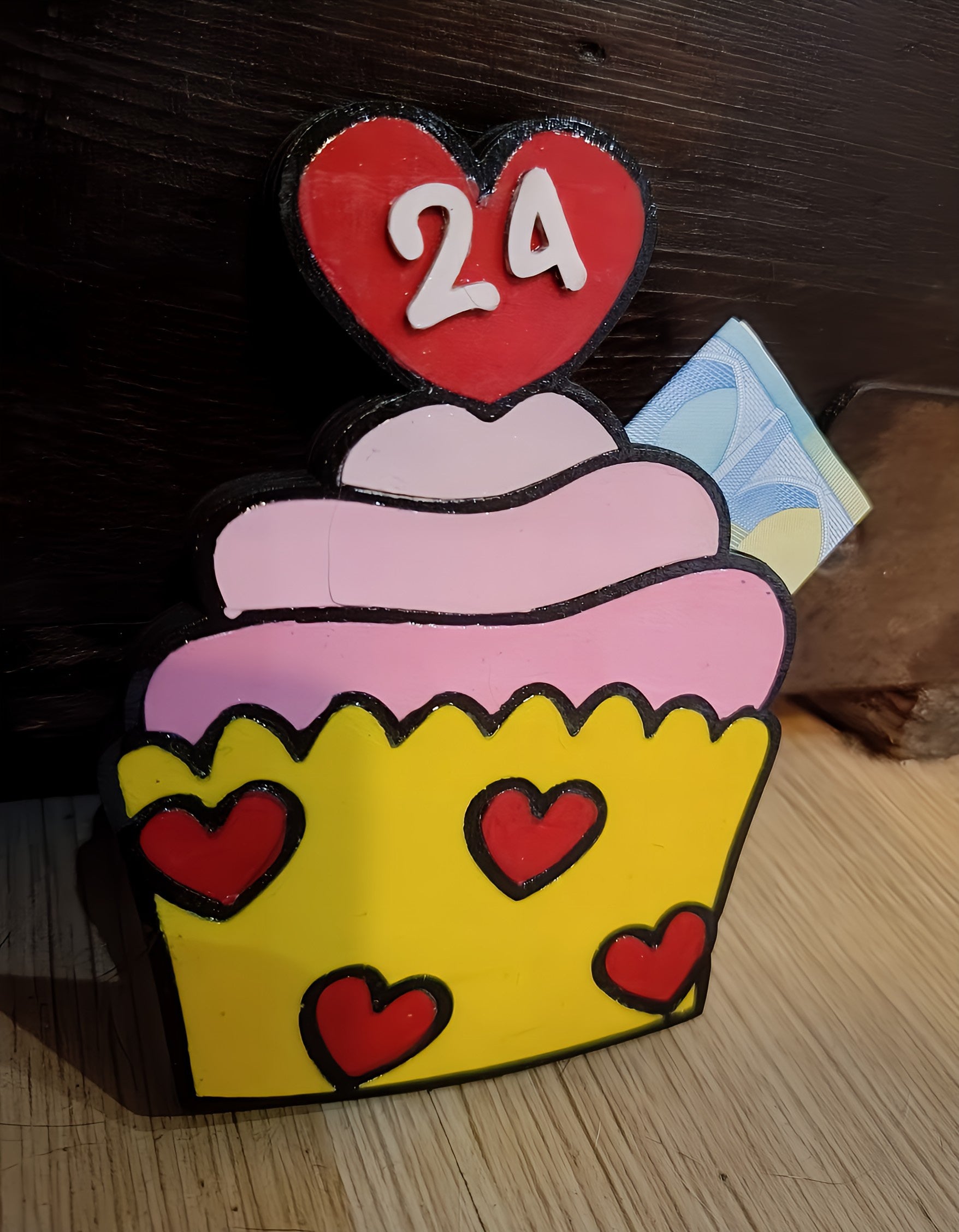 Colorful cupcake table sign with pink frosting, yellow base, red hearts, and number 24.