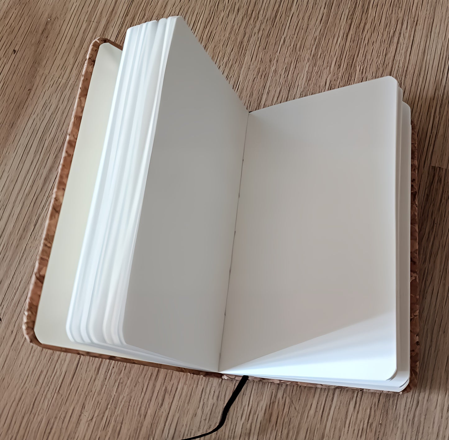 Open blank notebook with brown cover on wooden desk