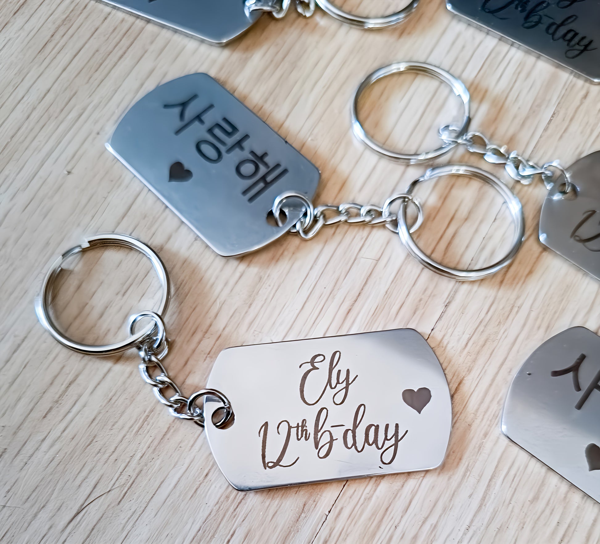 Personalized metal keychains with engraved text and heart on a wooden surface