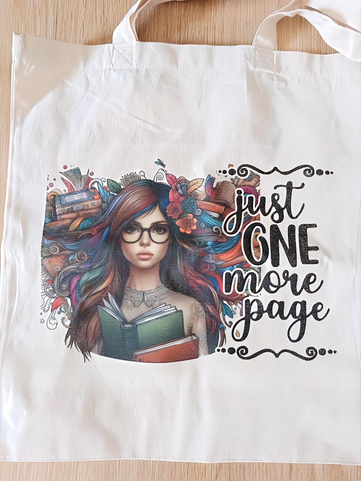 Tote bag with a colorful illustration of a woman holding books and text 'just one more page'.