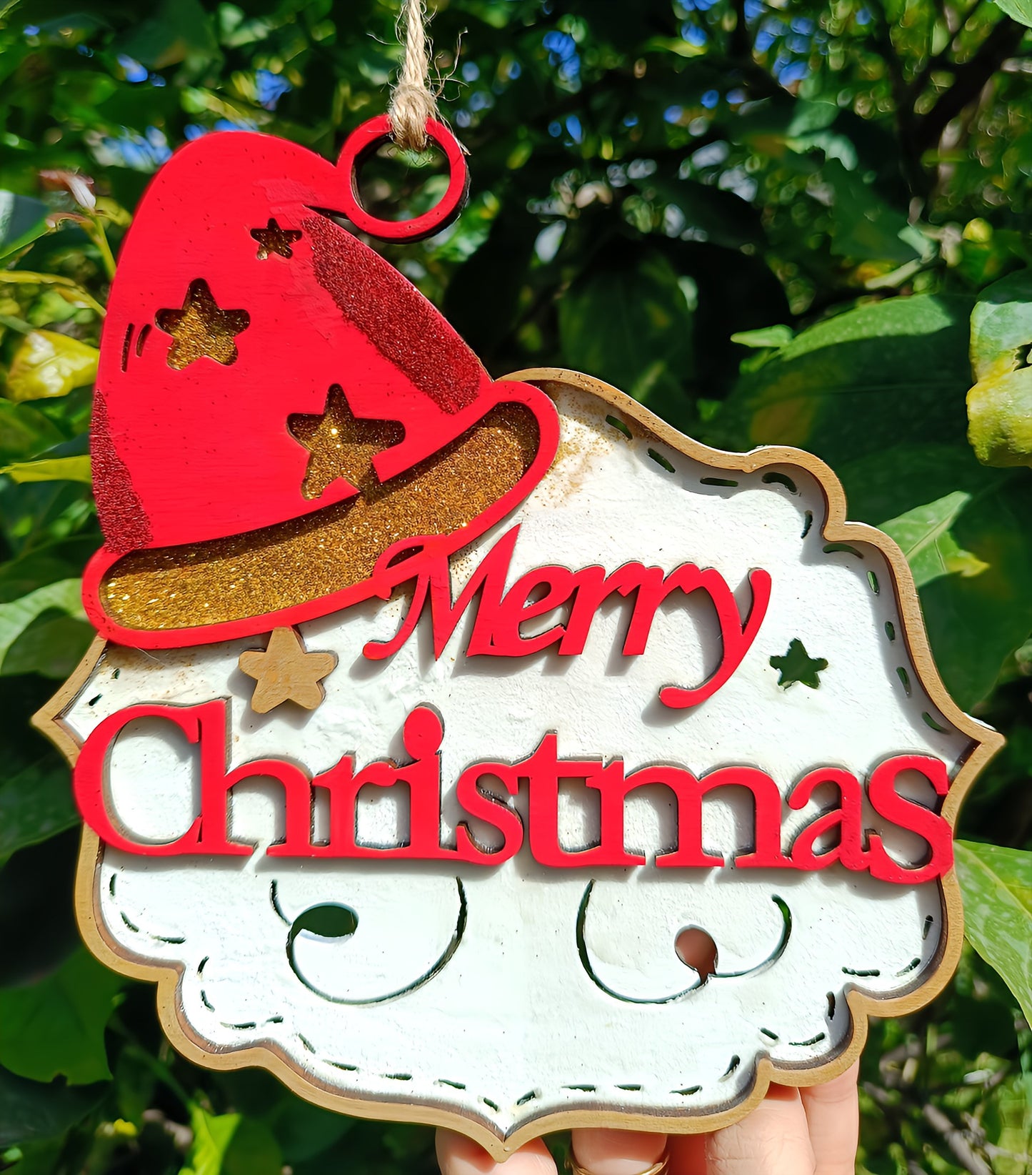 Wooden Merry Christmas sign with red Santa hat, outdoor greenery background