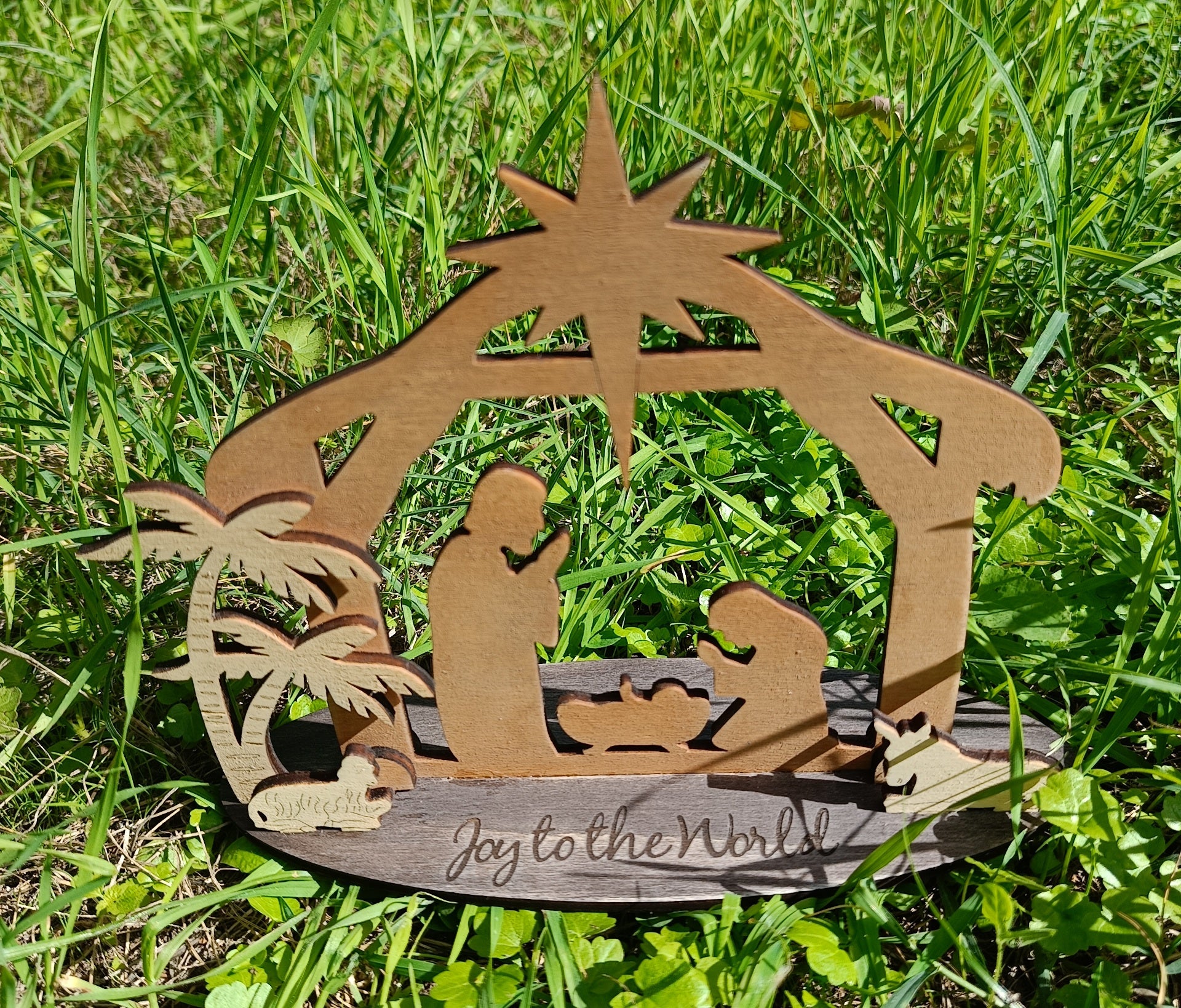 Wooden nativity scene 'Joy to the World' on green grass, outdoor Christmas decoration