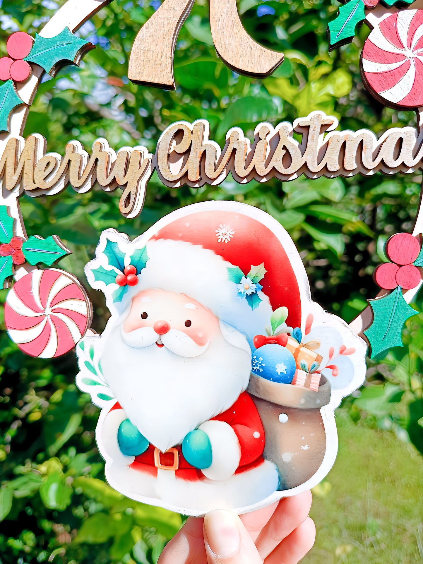 Hand holding festive Merry Christmas sign with cartoon Santa and gifts outdoors