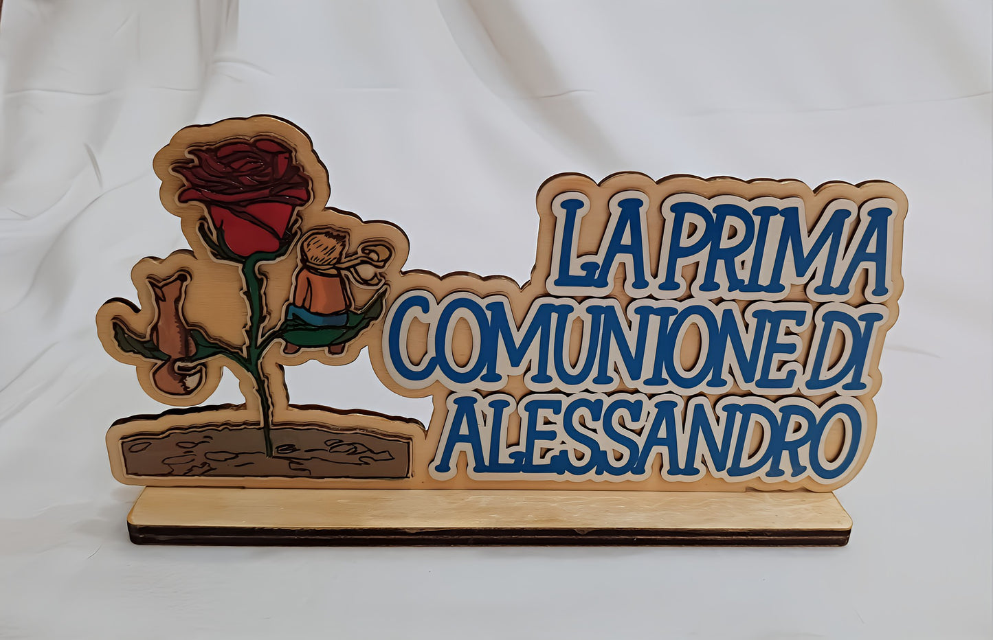 Wooden plaque with a red rose and Italian text 'La Prima Comunione di Alessandro' on stand