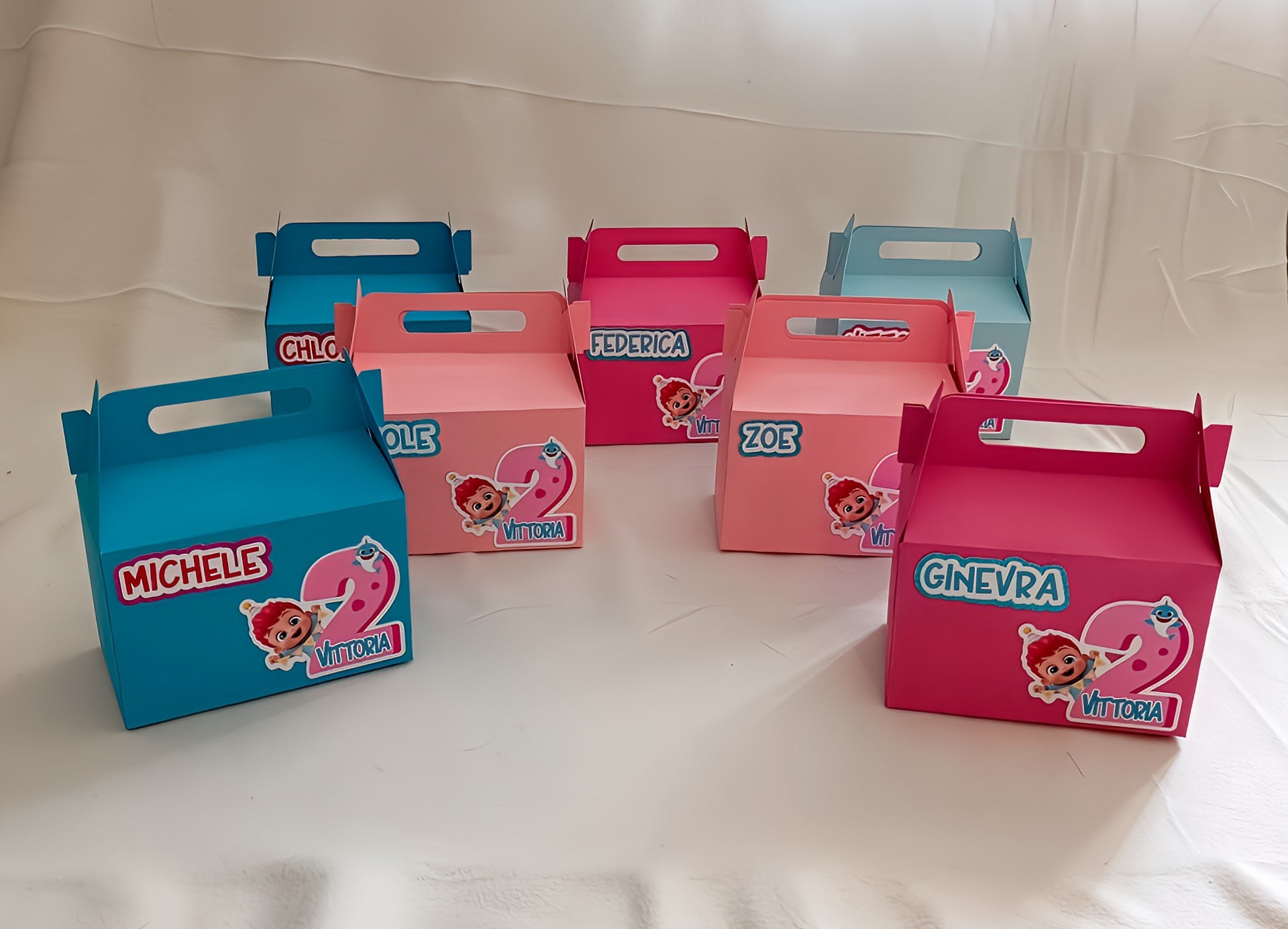 Colorful personalized kids' birthday party favor boxes with cartoon theme on white background