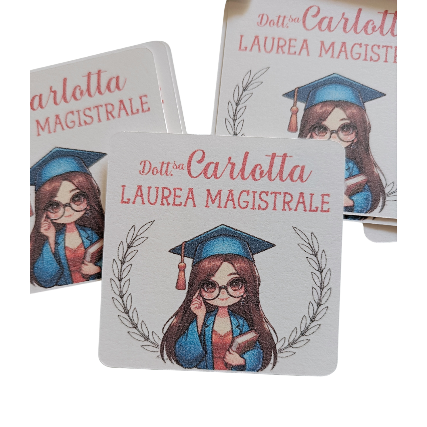 Graduation card with cartoon girl in cap and gown, holding book, Laurea Magistrale text.