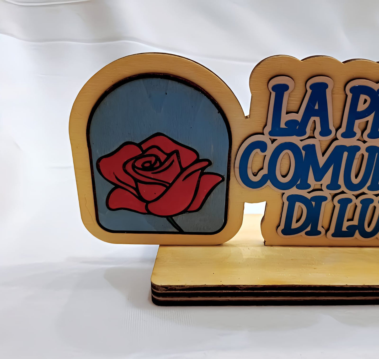 Wooden plaque with red rose graphic and partial blue Italian text on light background