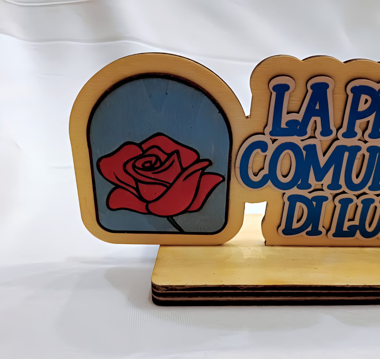 Wooden plaque with red rose graphic and partial blue Italian text on light background