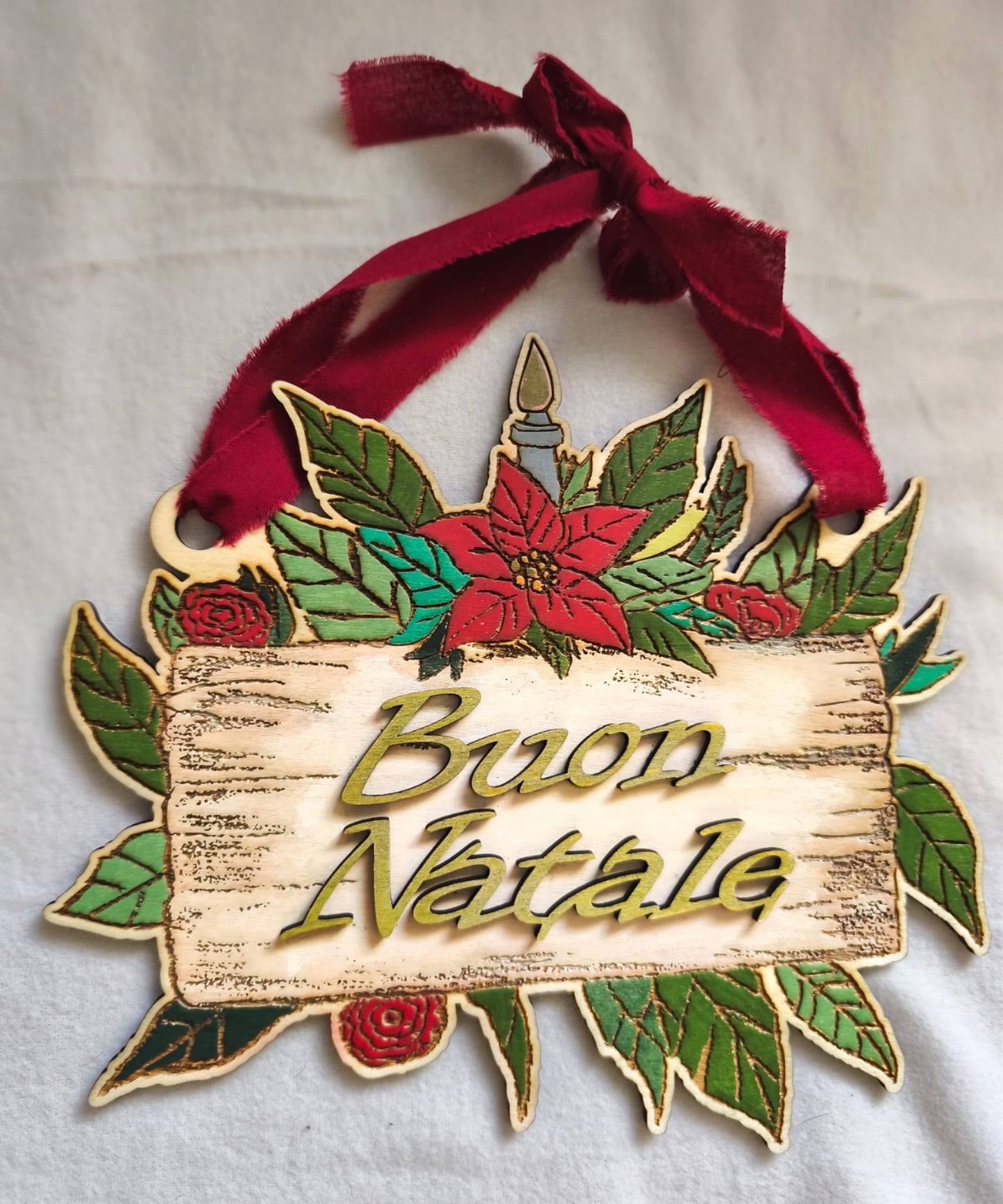 Wooden Buon Natale Christmas decoration with red ribbon, poinsettia, and green leaves