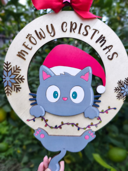 Cute cat Christmas wreath with 'Meowy Christmas' text, red bow, and festive lights outdoors