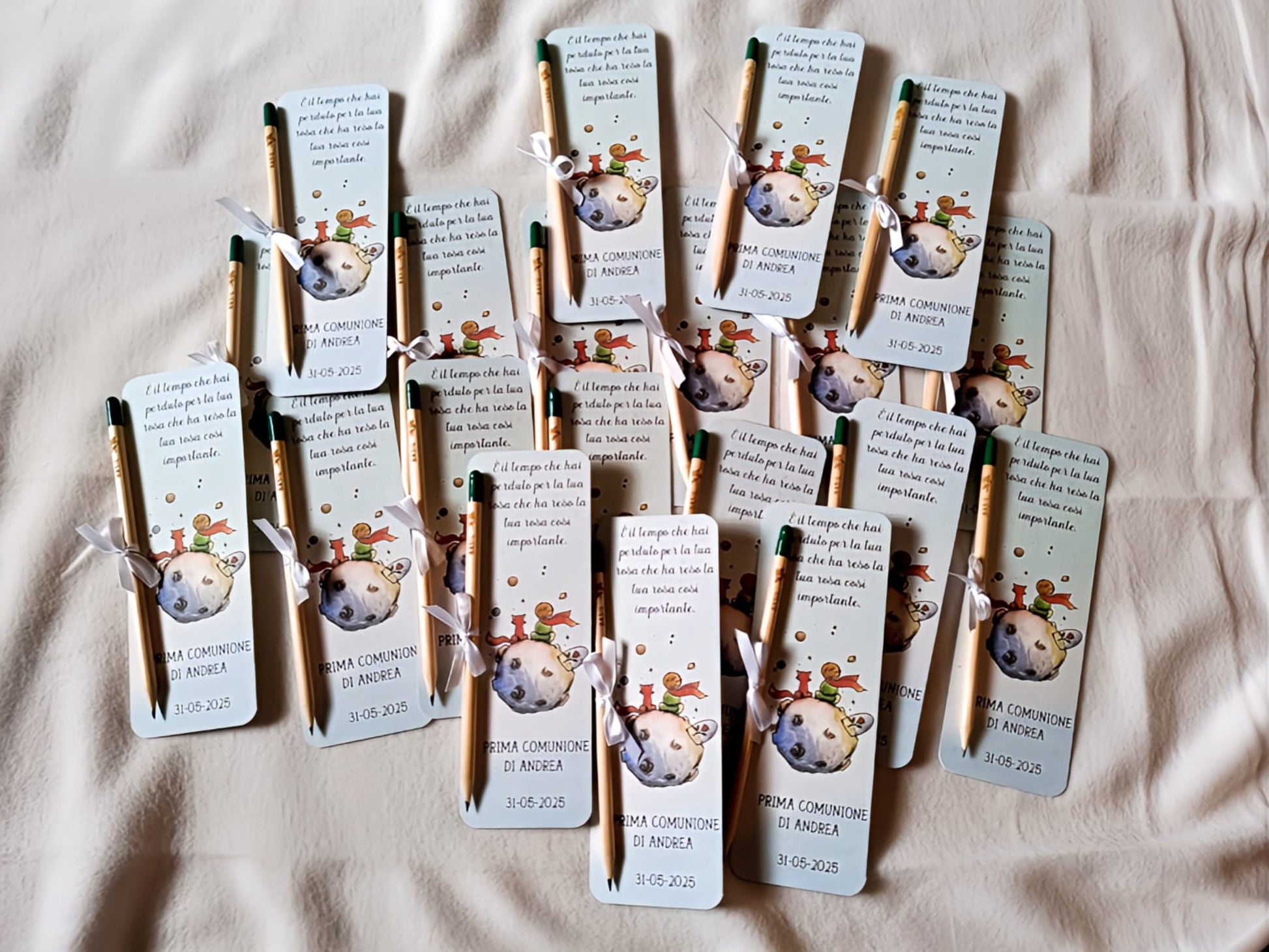 Little Prince themed communion bookmarks with attached pencils, arranged on a bed