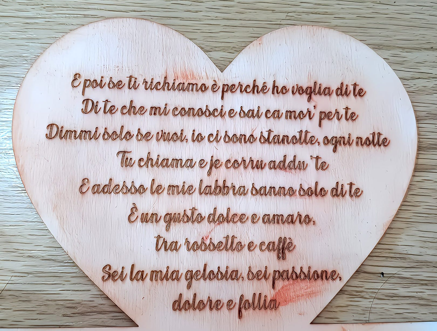 Italian love poem engraved on a wooden heart on a light wood surface