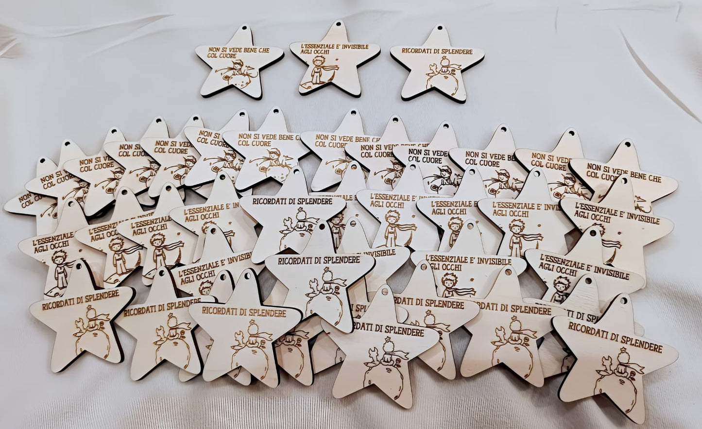 Wooden star-shaped ornaments with engraved Little Prince illustrations and Italian phrases